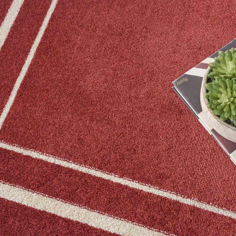Close-up of red rug with ivory stripe border and textured weave