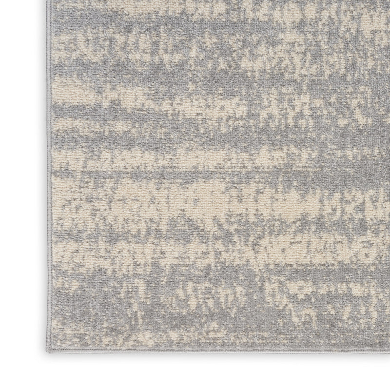 Gray and beige abstract square rug corner with dense short textured fibers.