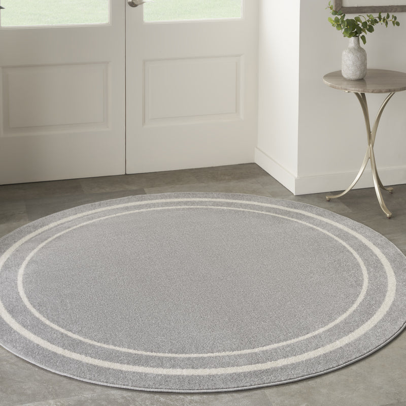 Round gray indoor outdoor rug with ivory concentric stripes in a room setting