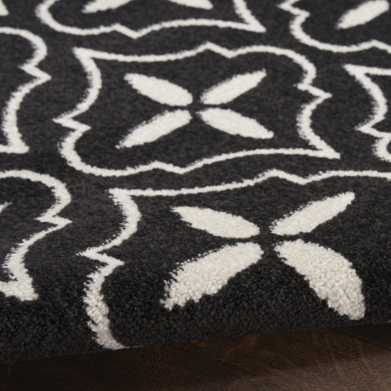 Close-up of black rug with ivory geometric floral and lattice pattern.