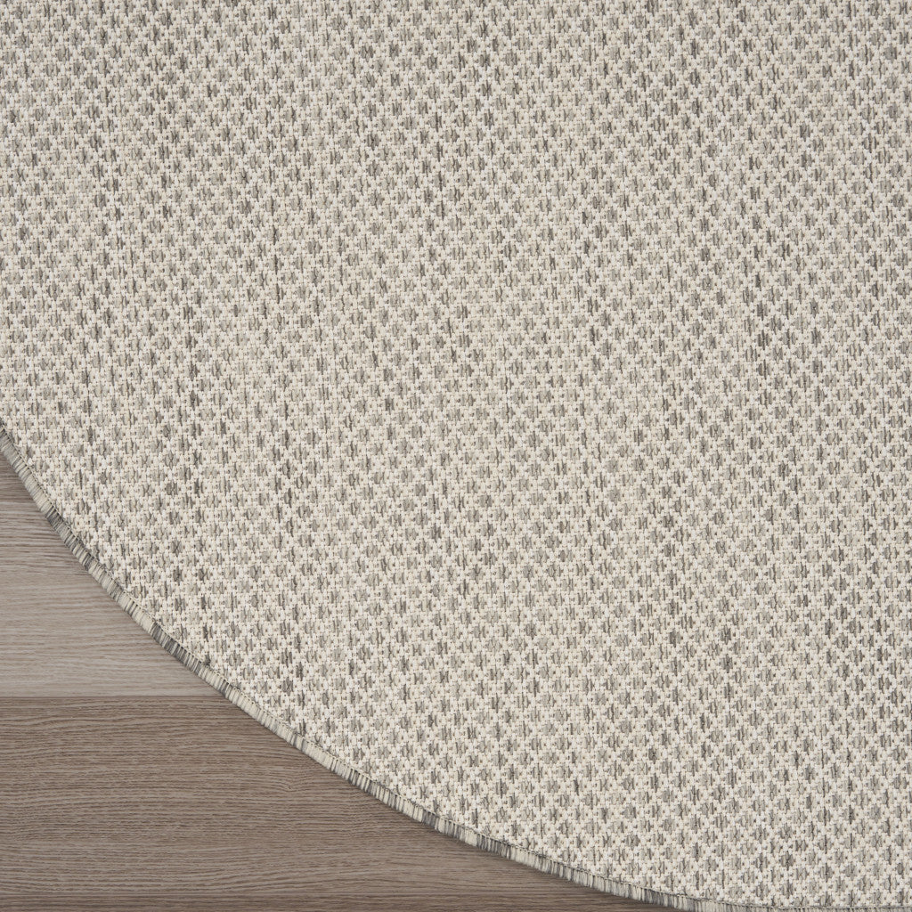 Round ivory area rug on wood floor with silver-tone geometric lattice and bound edge