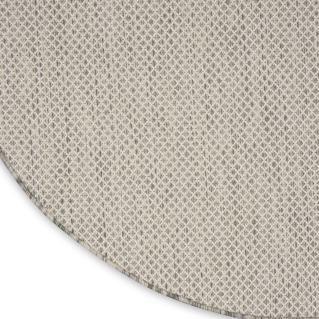 Round ivory rug corner view with bound edge and silver-tone geometric lattice