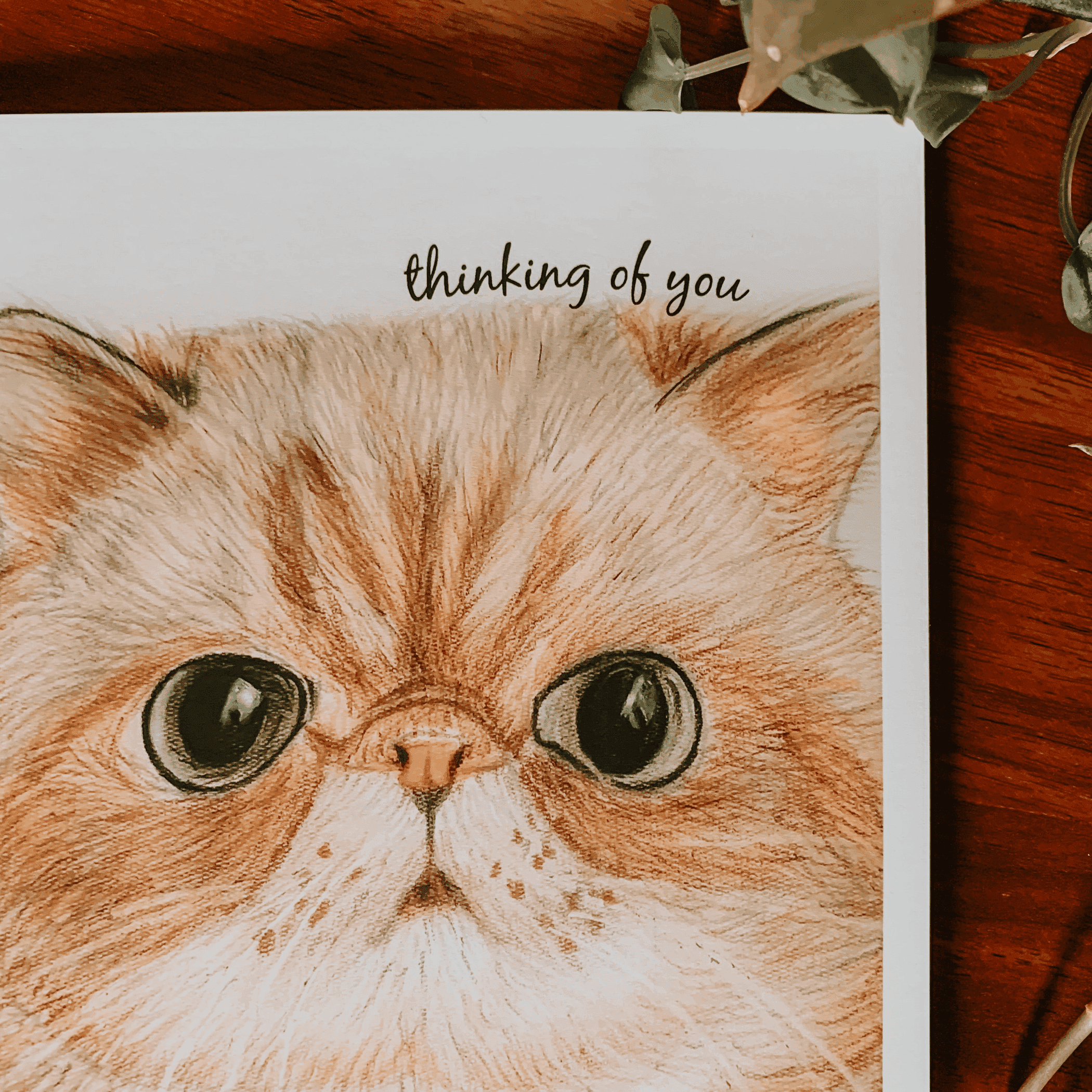 Greeting card with orange tabby cat face illustration and 'thinking of you'
