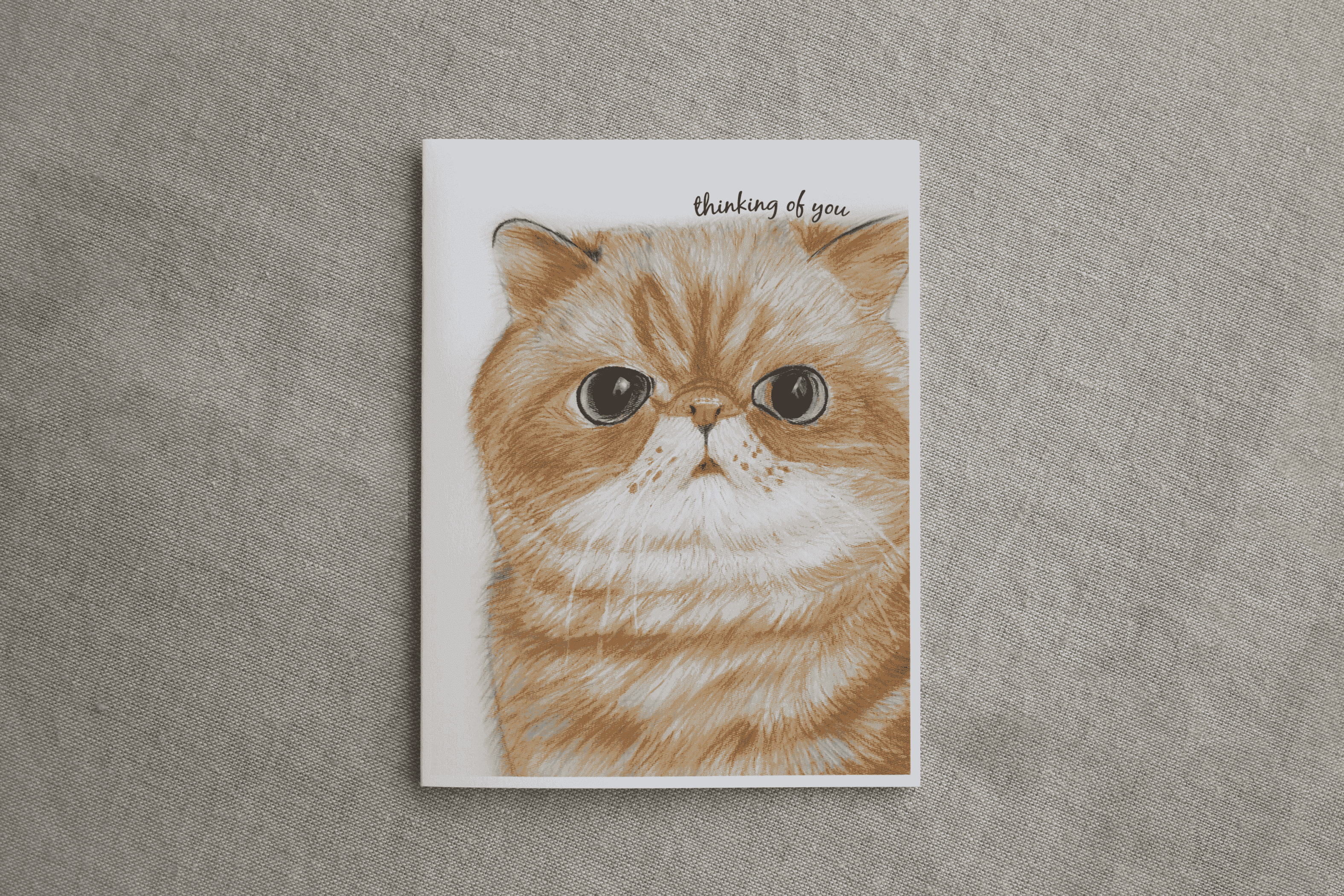 Greeting card featuring orange tabby cat head illustration and 'thinking of you' text