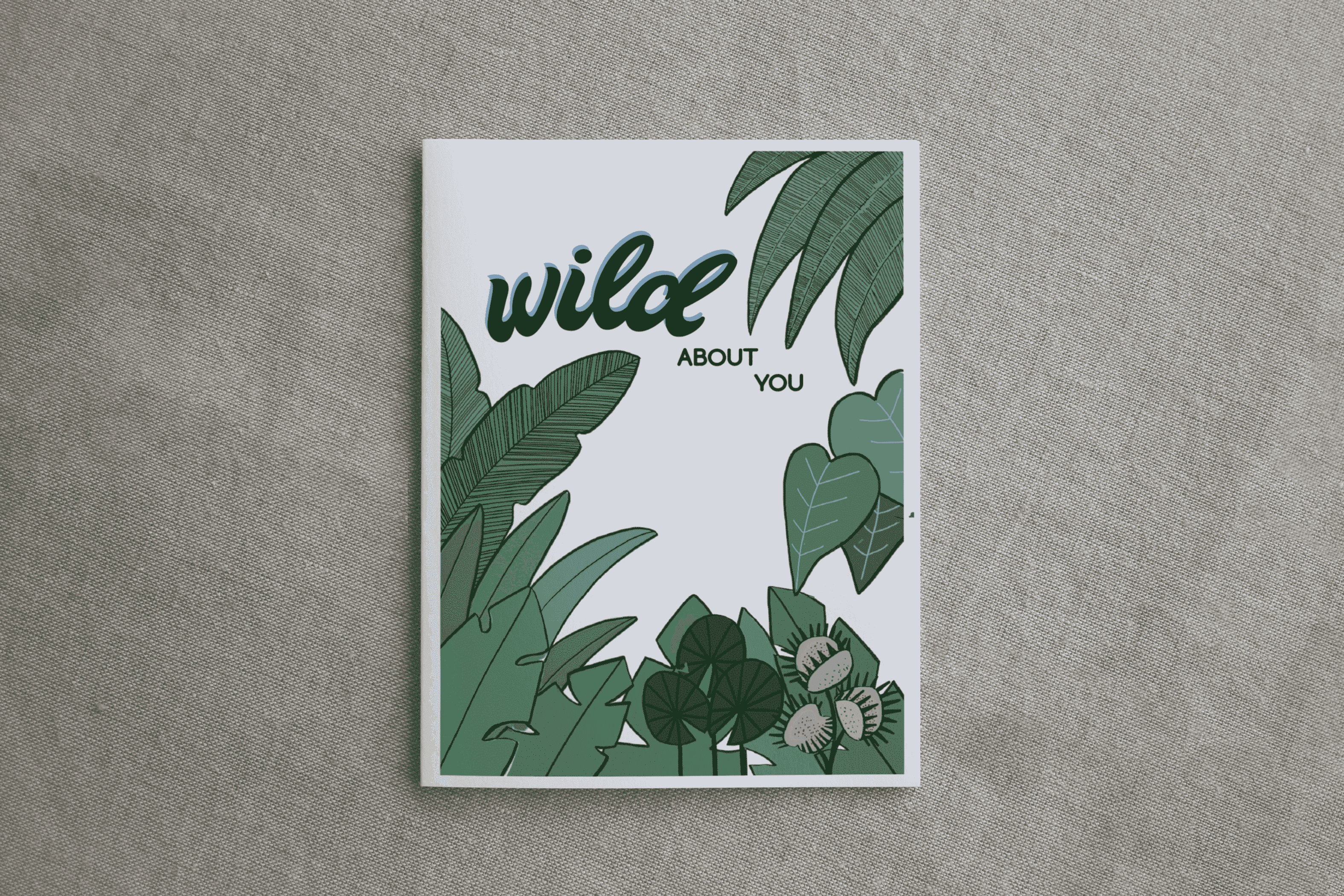 Square botanical greeting card on gray fabric with green leaves and "wild ABOUT YOU" text.