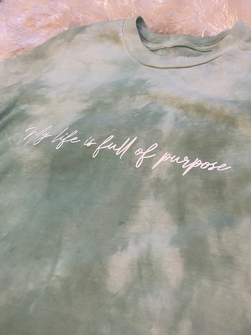 Plant-dyed sage green affirmation T-shirt with white script text across chest