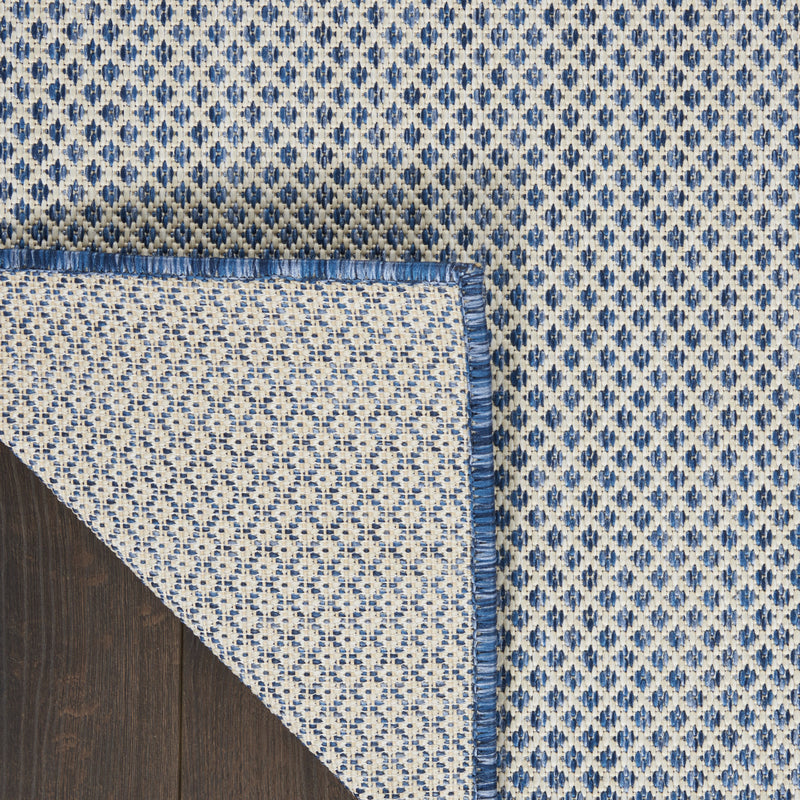 Indoor/outdoor area rug with fringed edge and blue-and-ivory diamond pattern