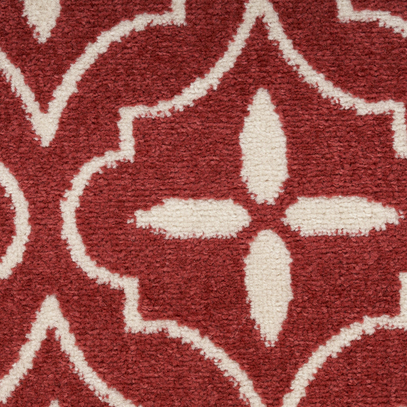 Close-up of brick red area rug with ivory eight-point star and outline trellis pattern.