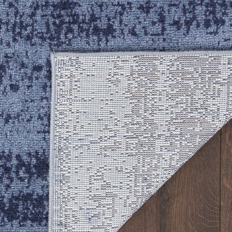 Reversible blue-and-navy abstract area rug corner with white underside