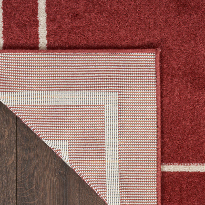 Brick red area rug corner showing ivory binding and close woven texture
