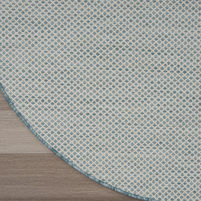 Round blue geometric power loom rug corner close-up with patterned face and blue border