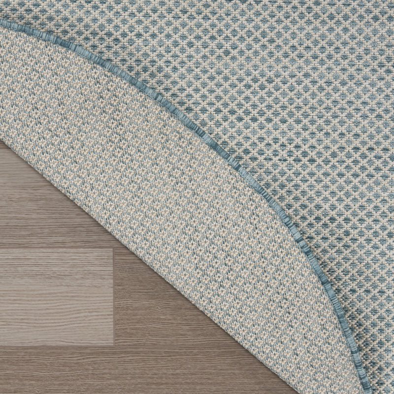 Blue round area rug showing patterned pile and narrow teal-blue edge along the curve