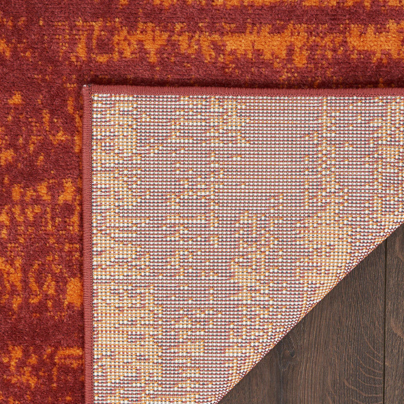 Red and orange abstract area rug corner with dark bound edge detail