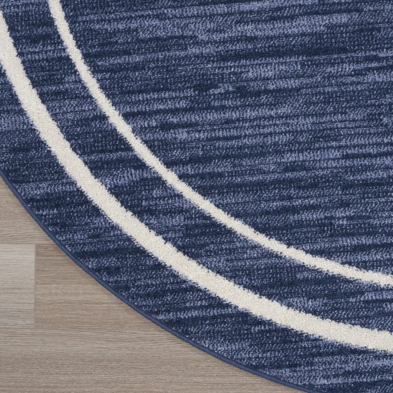 Round navy blue area rug with ivory striped edging; textured surface and curved border.