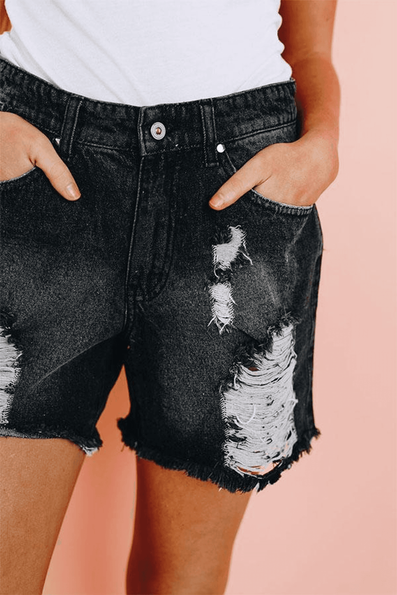 Black distressed denim shorts detail: ripped patches, frayed hem, button waistband