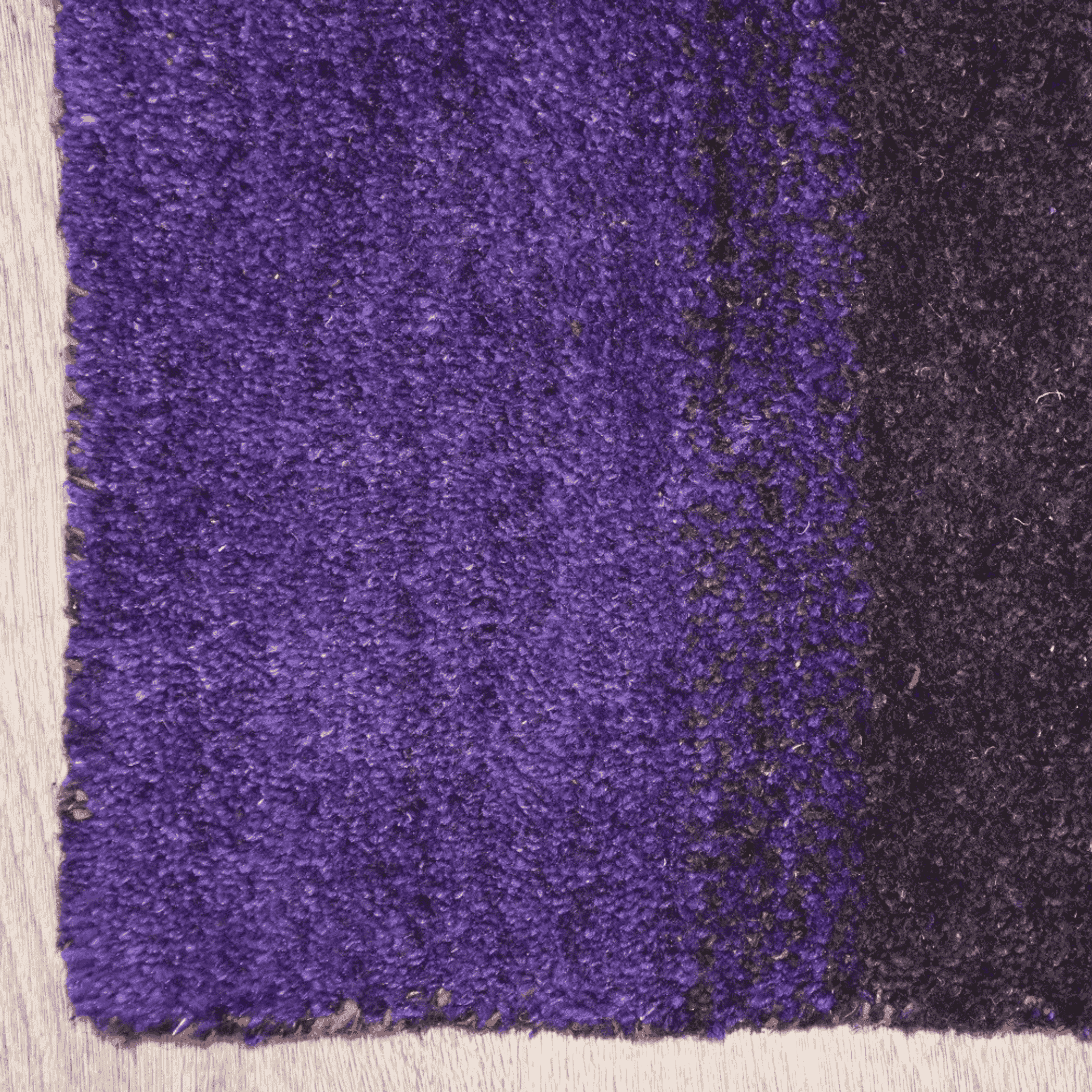 Purple area rug with dark corner edge and subtle gold speckle texture