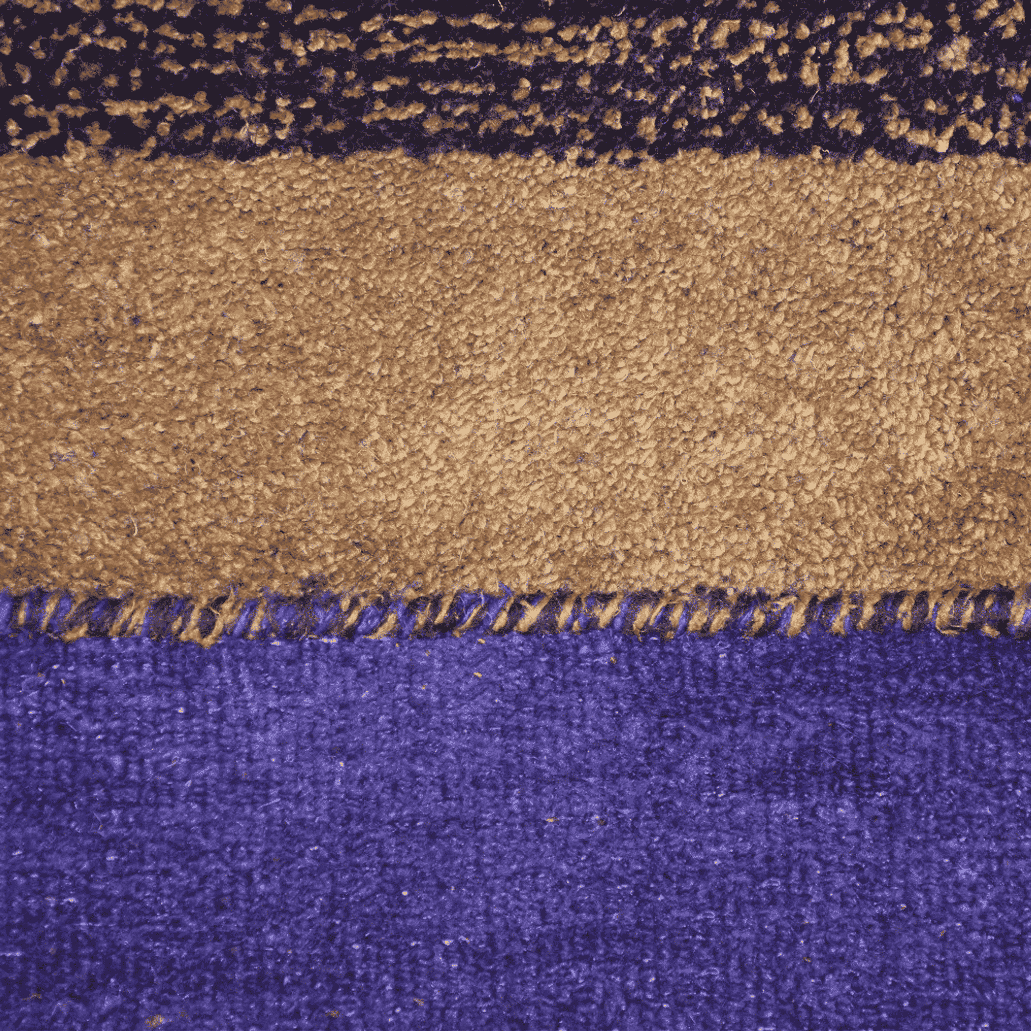 Rug pile closeup showing tan and brown speckled band with purple section and fringe