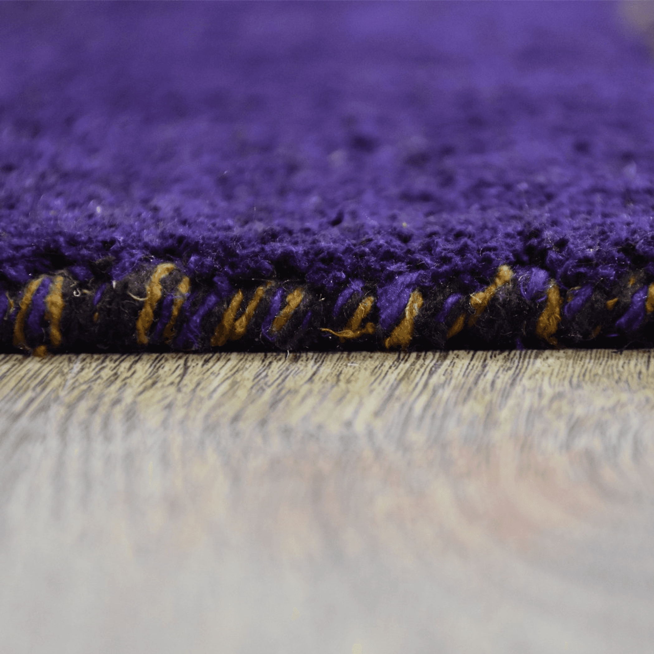 Purple area rug fringe detail with gold and dark thread accents along border