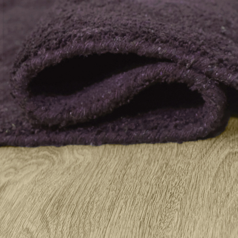 Dark purple hand-knotted silk-mix area rug, rolled edge showing underside binding