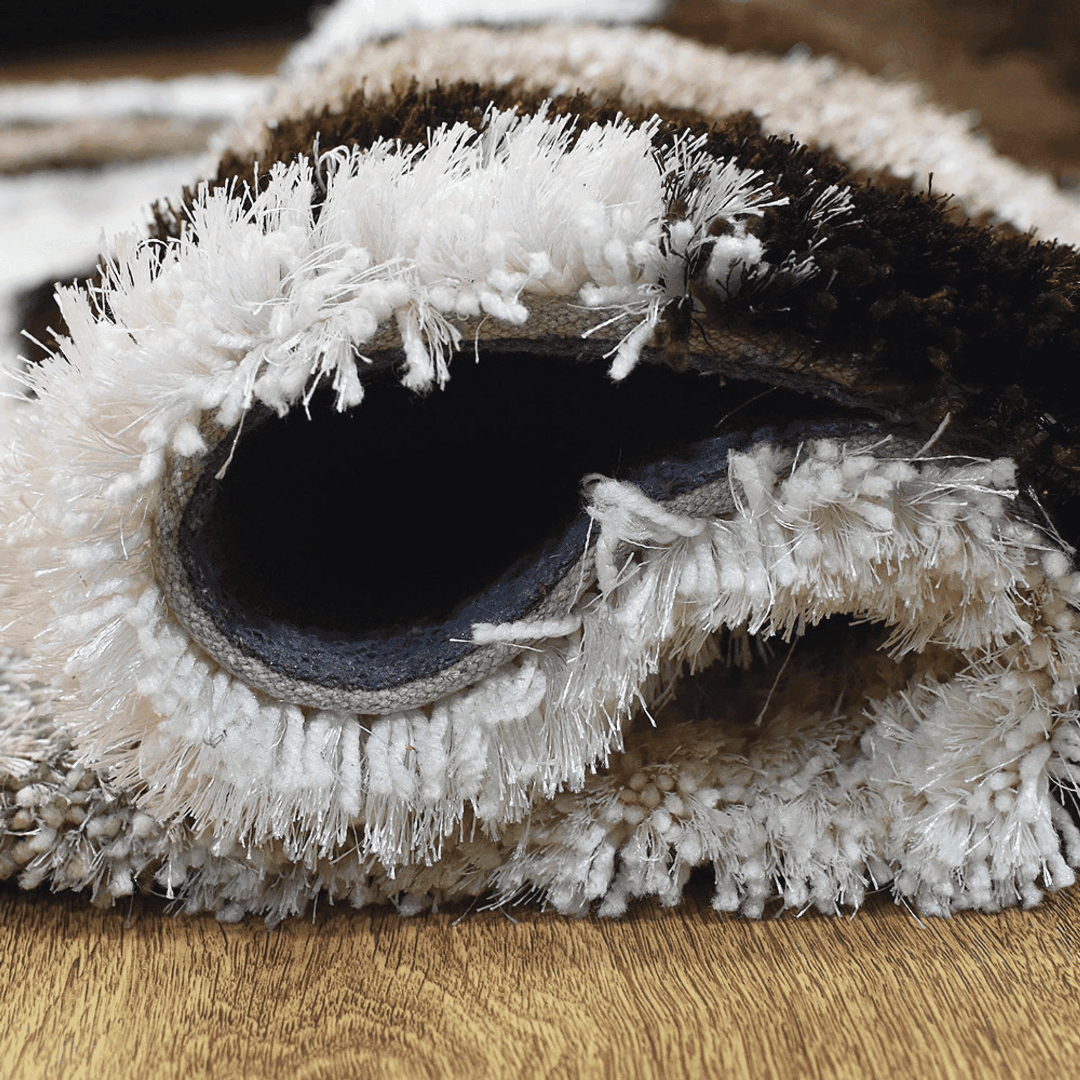 Shag area rug edge showing stitched underside backing in dark and white
