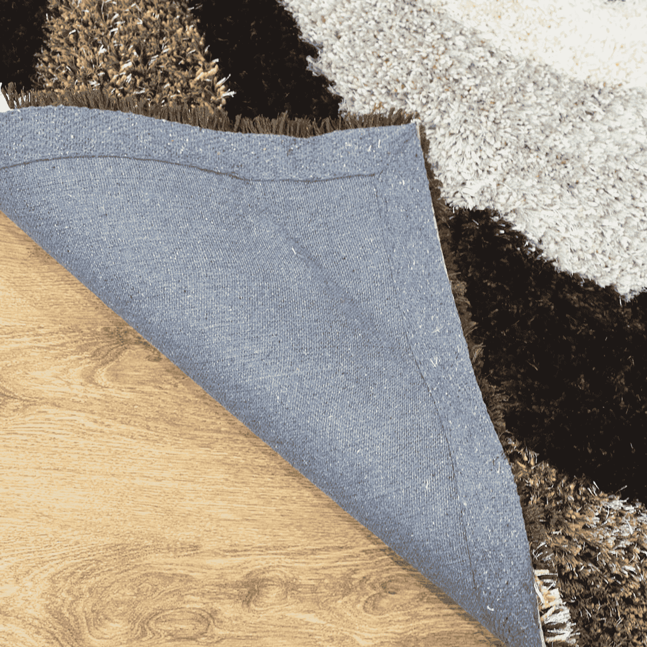 Shag area rug corner with gray fabric backing beneath the pile