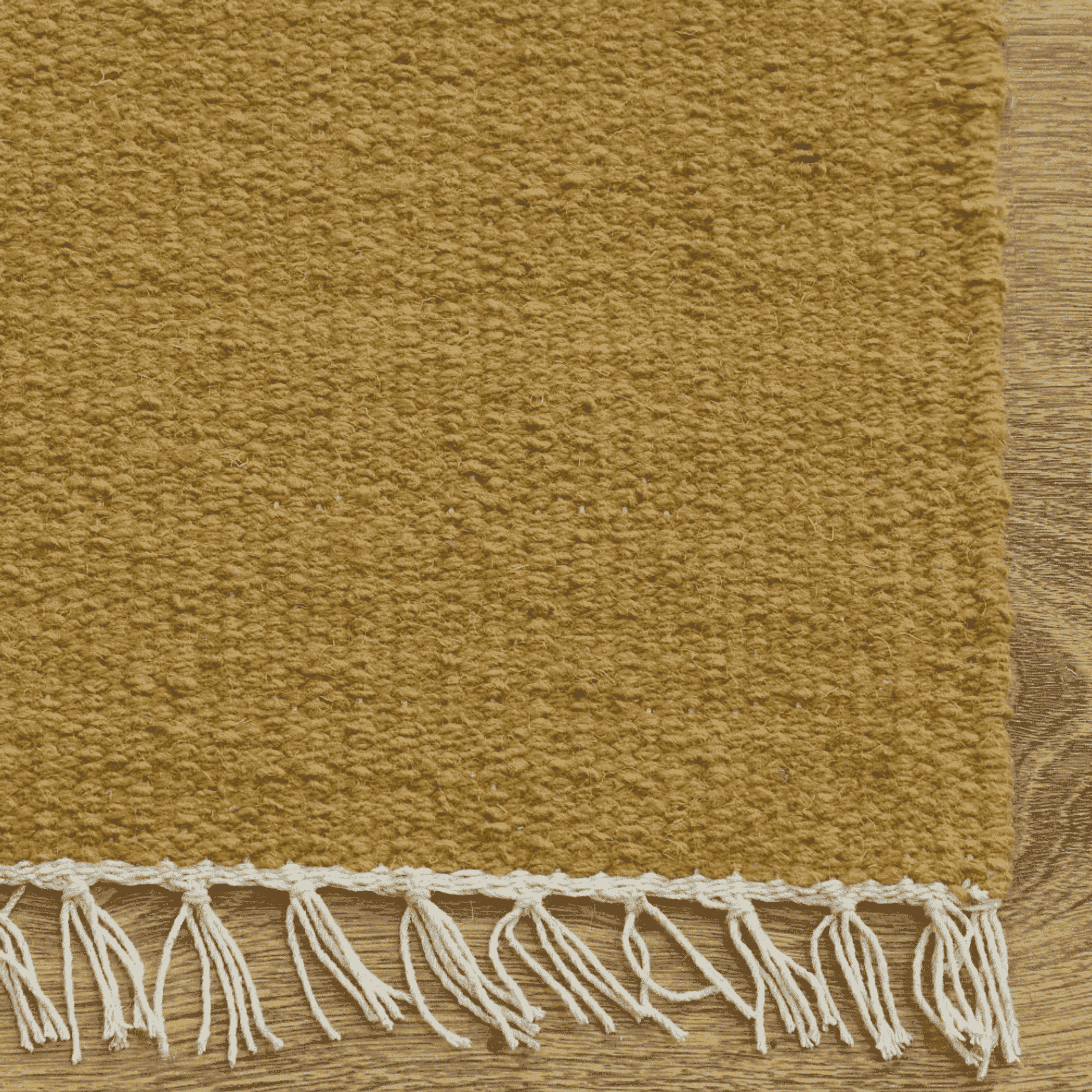 Solid mustard wool rug close-up showing flat weave and white fringe