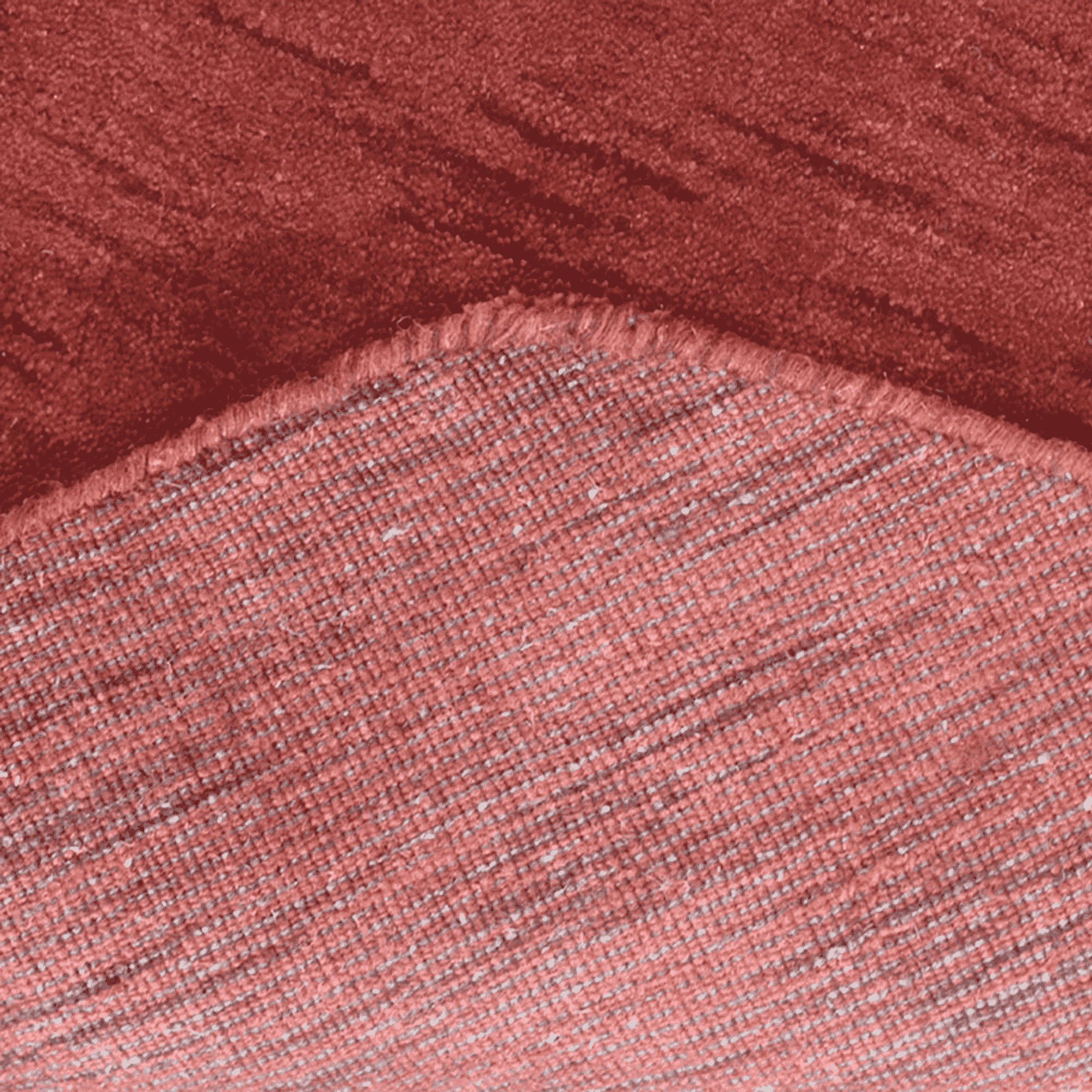 Red and light pink textured rug surface with short pile, angled close-up