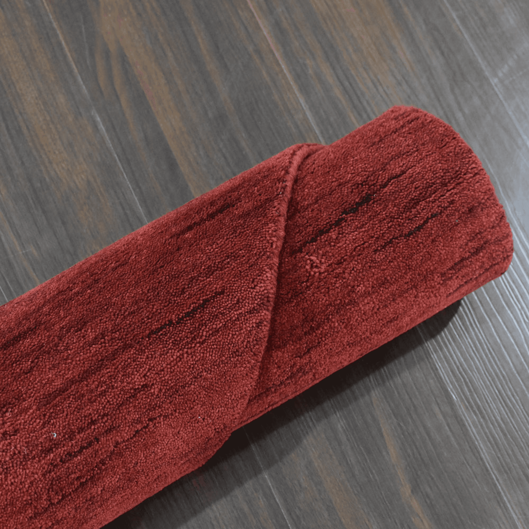 Red plush rug with short pile, rolled edge close-up