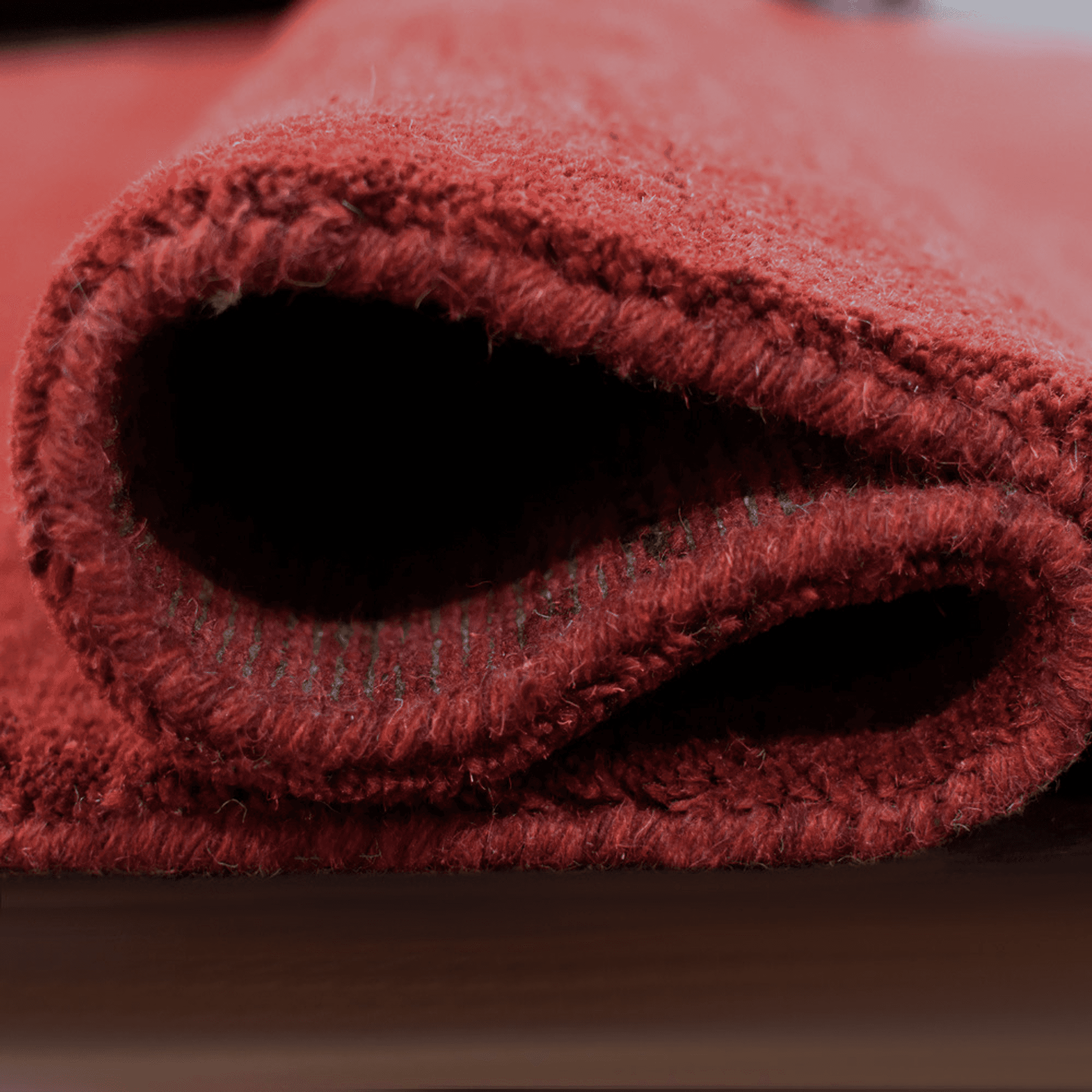 Rolled red rug showing thick short pile and underside close-up