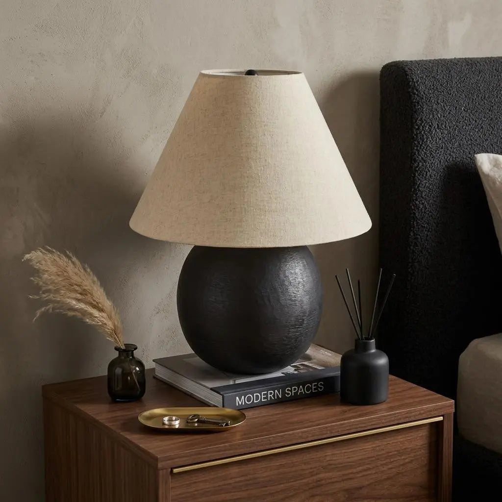 Black ceramic table lamp with beige linen shade, modern design on a wooden nightstand, enhancing contemporary decor.