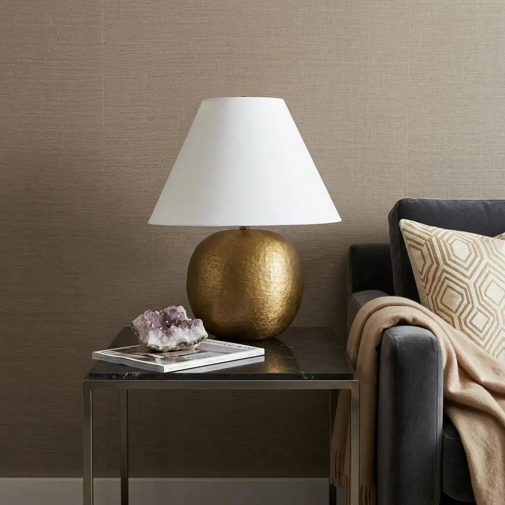 Gold ceramic table lamp with a white fabric shade, styled with a marble side table and decorative accents.