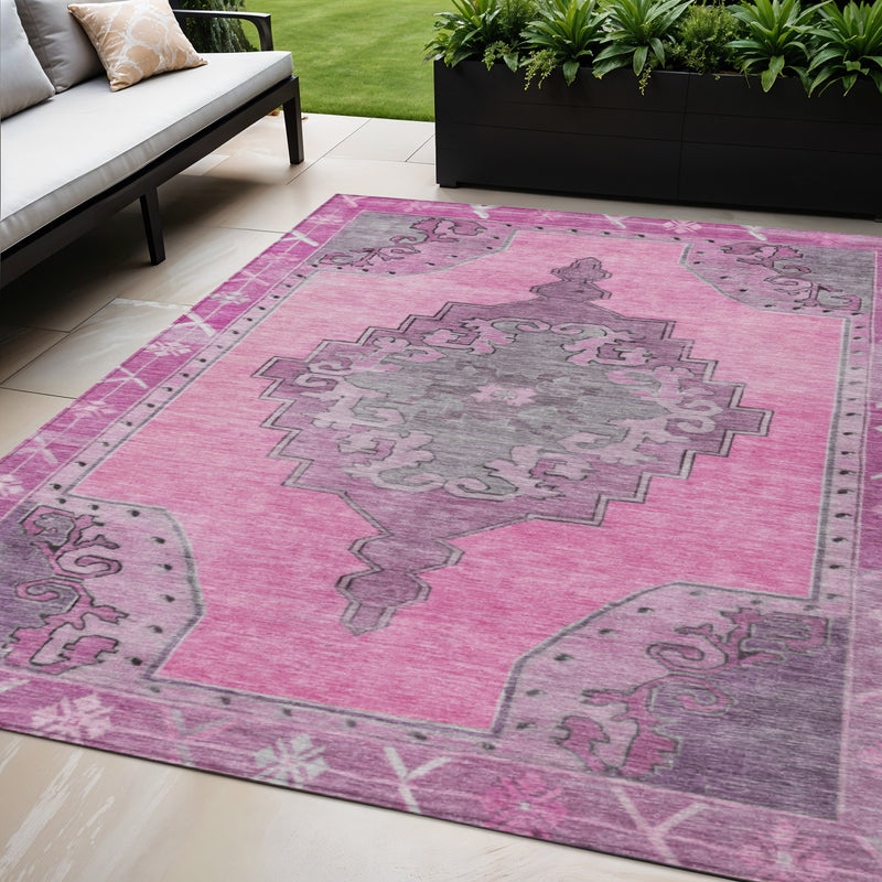 Pink geometric area rug with gray center motif, corner details, and textured surface
