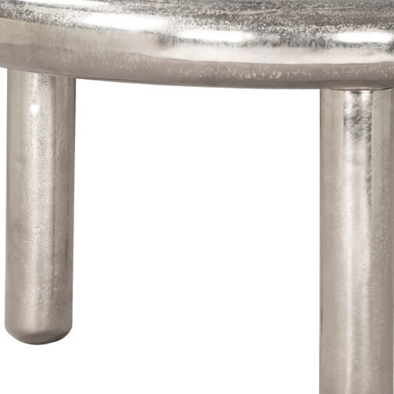 Silver pedestal legs and brushed metal tabletop edge of a round coffee table