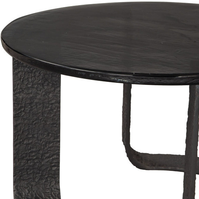 Close-up of black round coffee table top edge and textured pedestal base