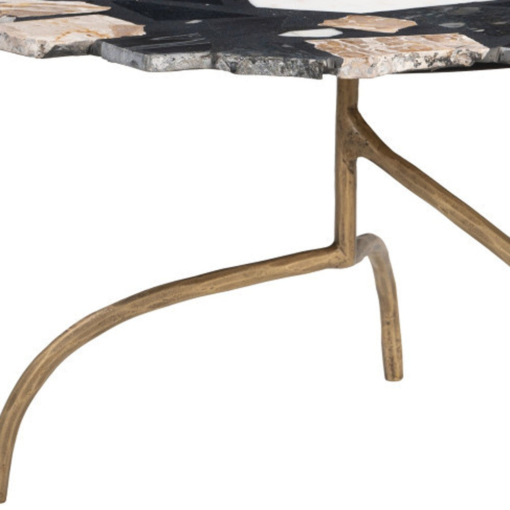 Close-up of iron pedestal legs under a black, white, and gold terrazzo mosaic table top