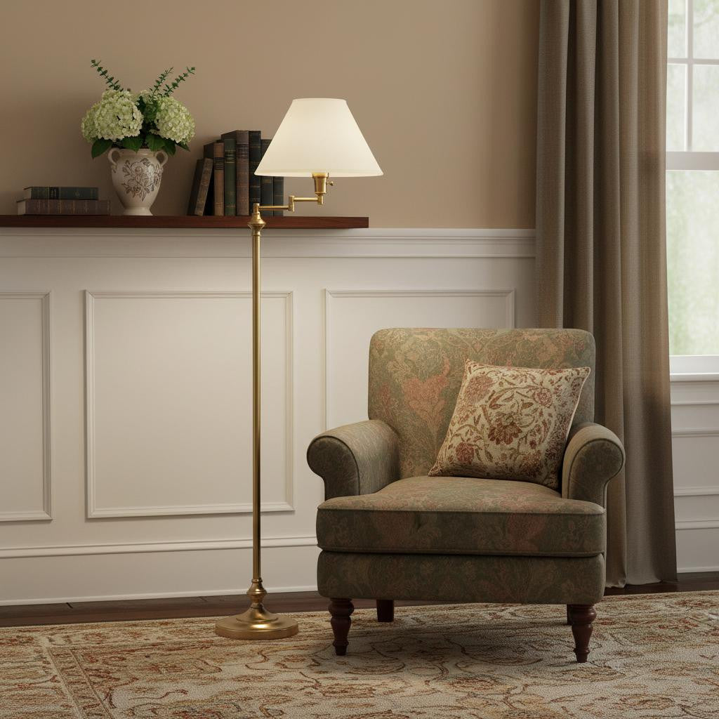 Antique brass floor lamp with white fabric shade next to a floral-patterned green armchair in a cozy living room setting.