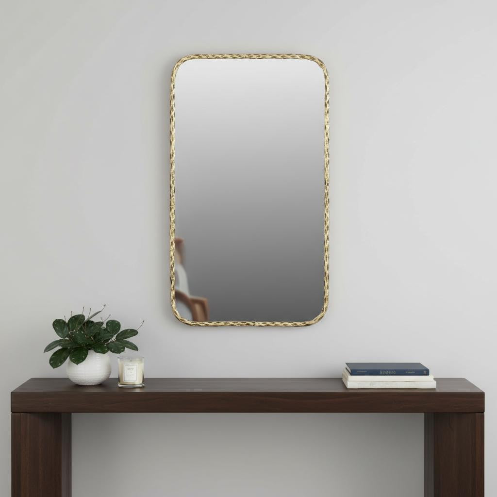 Rectangular accent mirror with hammered gold-tone brass frame above dark wood console