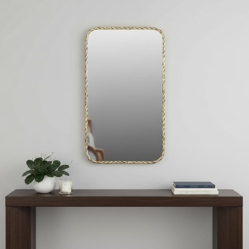 Rectangular accent mirror with hammered gold-tone brass frame above dark wood console