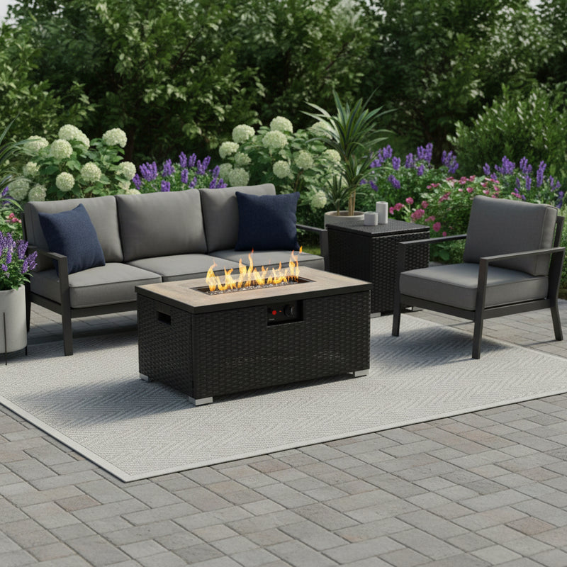 Outdoor rectangular propane fire pit with black wicker table and flame in center