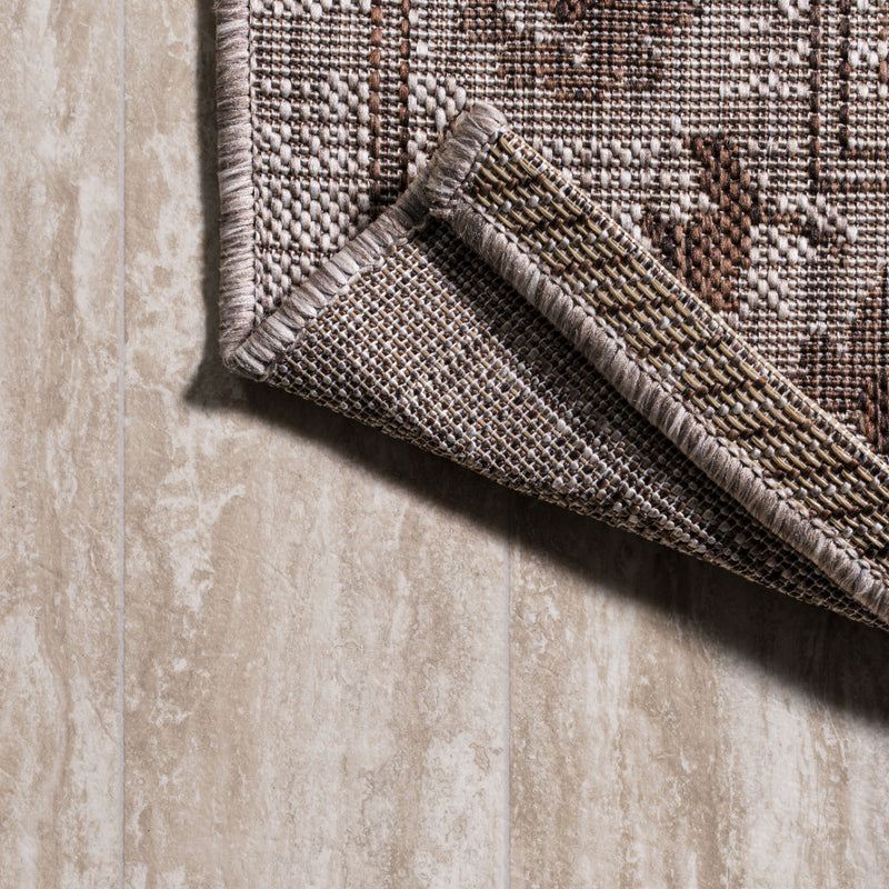 Close-up of rug edge with textured weave in beige and brown medallion pattern.