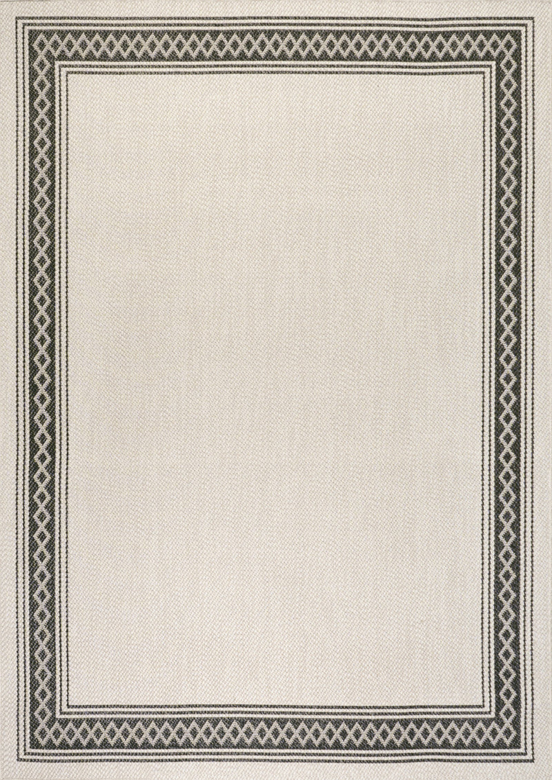 Cream indoor outdoor area rug with black patterned border, close-up view
