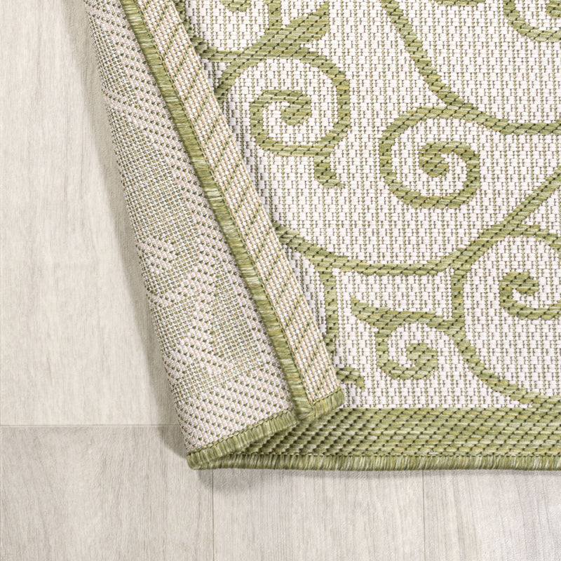 Indoor-outdoor area rug corner detail, cream fabric with green stitched border