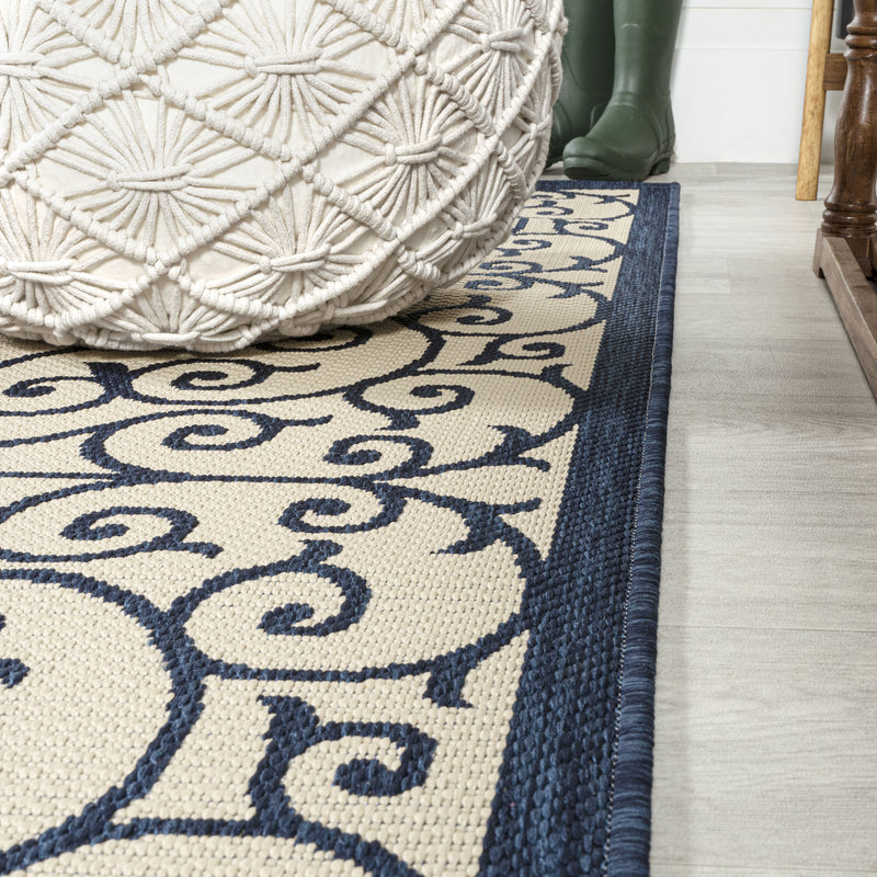 Round rug corner detail with navy border and beige scrollwork pattern