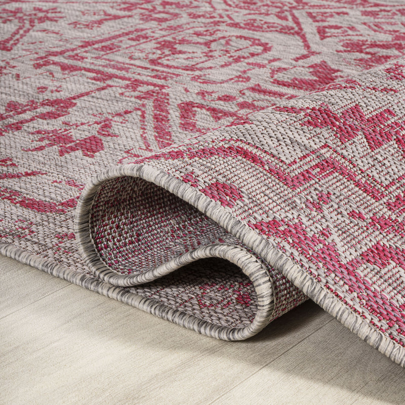 Textured edge of light gray and fuchsia medallion indoor/outdoor area rug