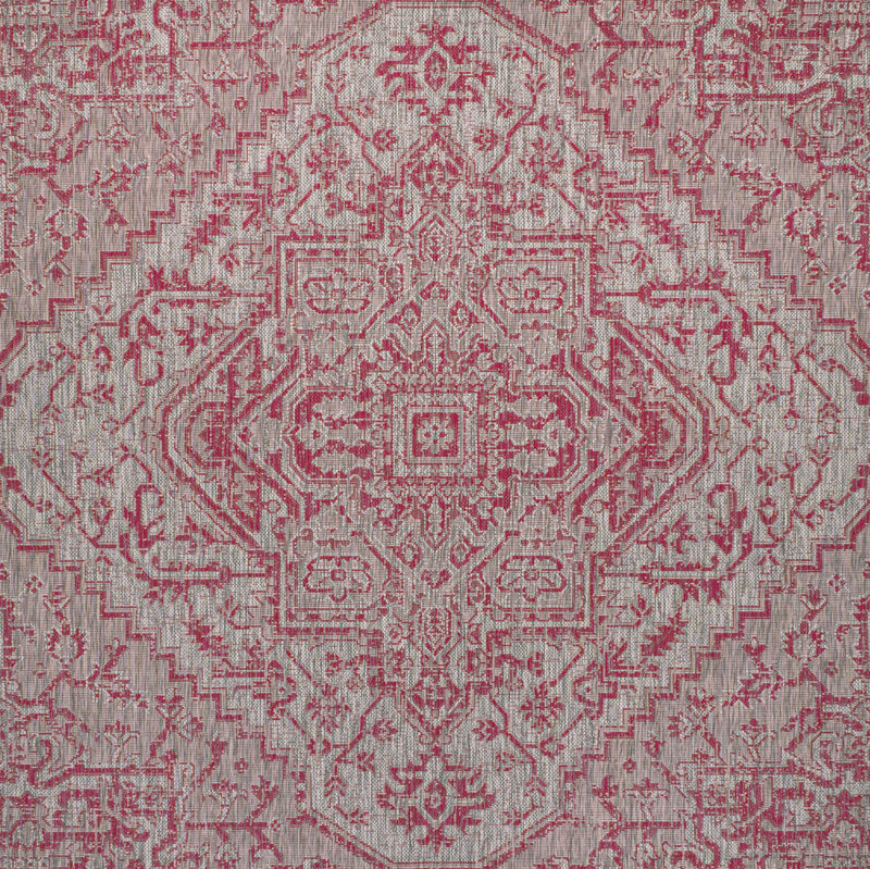 Close-up of light gray area rug with dense fuchsia geometric medallion motifs