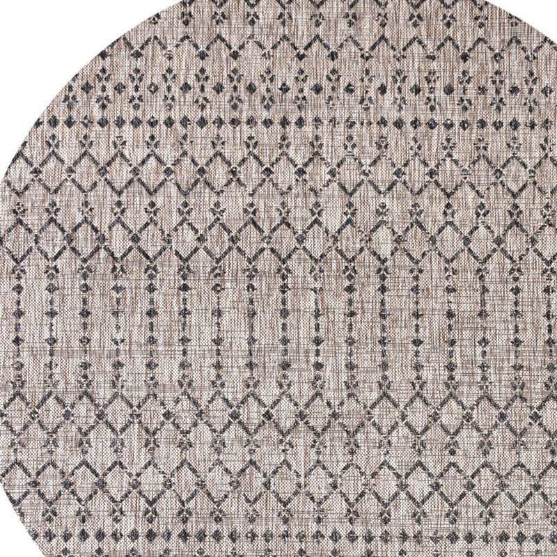Round indoor/outdoor area rug with beige base and black trellis diamond pattern.