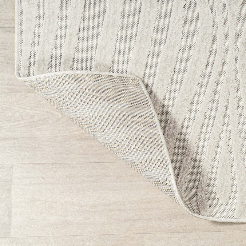 Round abstract rug corner showing cream and ivory striped weave texture.