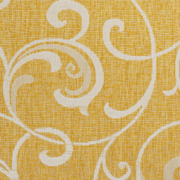 Yellow area rug with cream swirling floral medallion pattern, close-up texture.