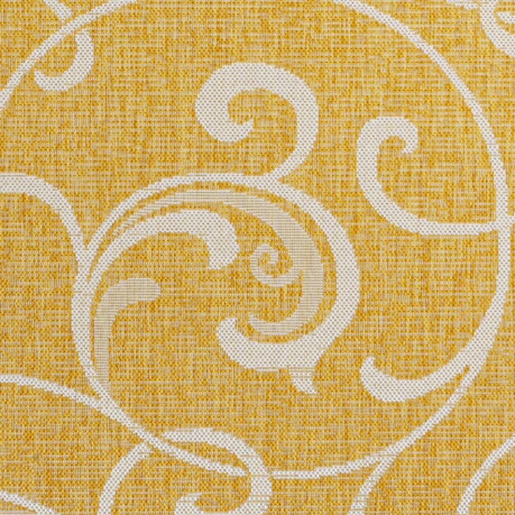 Yellow area rug with cream ornate swirls and scrollwork floral motif, close-up