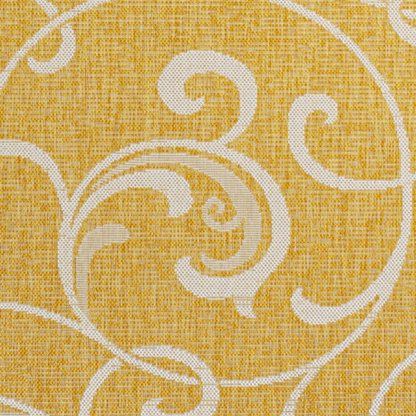 Yellow area rug with cream ornate swirls and scrollwork floral motif, close-up